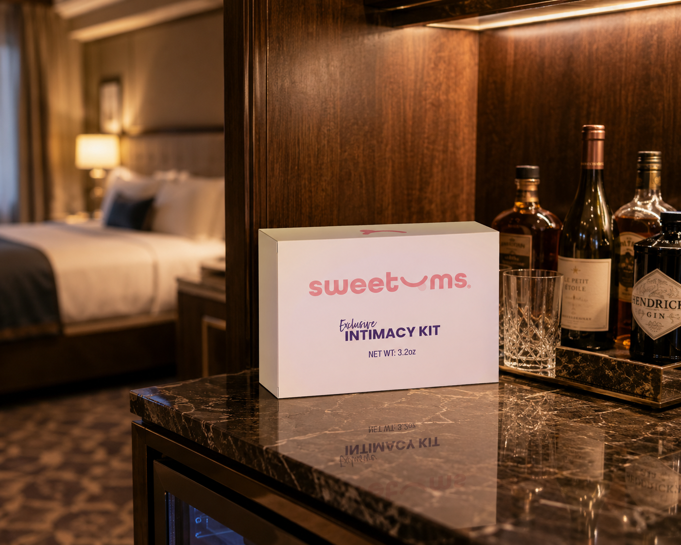 Sweetums intimacy kit on a marble surface with bottles in a hotel room setting